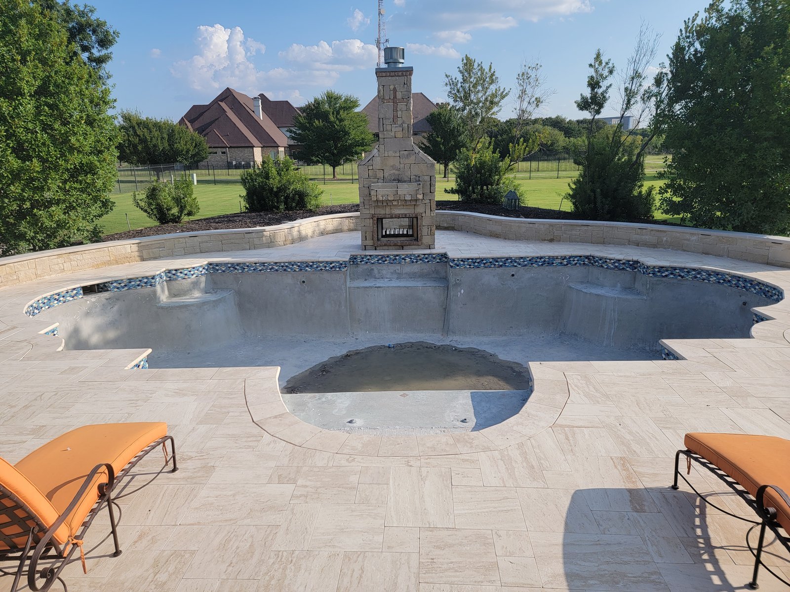pool-excavation-empty-backyard-with-lounge-chairs-and-fireplace